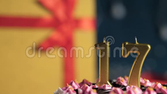 生日蛋糕17号金色蜡烛用打火机点燃蓝色背景礼品黄色盒子用红丝带系好视频的预览图