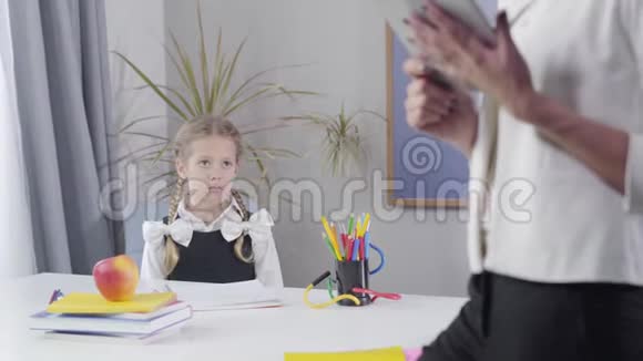 可爱的白种人女学生在桌子前跳起来做胜利的手势无法辨认的女家庭教师视频的预览图