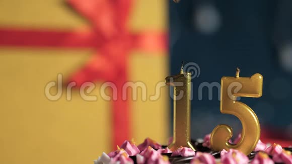 生日蛋糕15号金色蜡烛用打火机点燃蓝色背景礼品黄色盒子用红丝带系好视频的预览图