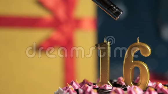 生日蛋糕16号金色蜡烛用打火机点燃蓝色背景礼品黄色盒子用红丝带系好视频的预览图