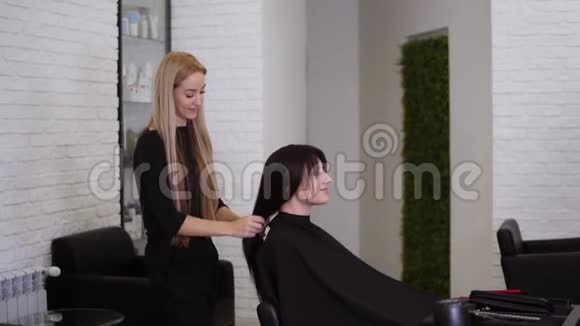 女理发师刚刚完成了她的女客户的工作她的长发直棕色头发女人微笑着视频的预览图