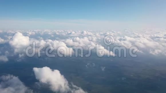 美丽的陆地鸟瞰和白色蓬松的云通过飞行飞机的窗户视频的预览图