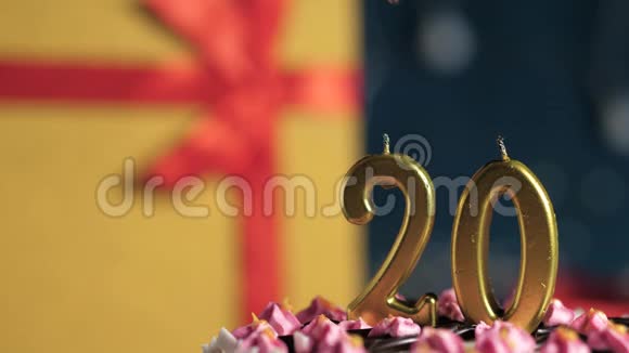 生日蛋糕20号金色蜡烛用打火机点燃蓝色背景礼品黄色盒子用红色丝带系好视频的预览图
