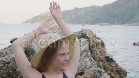 穿着柳条帽在海滩上摆姿势的漂亮少女视频的预览图