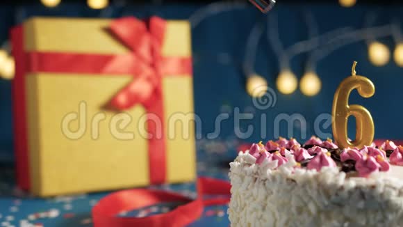 白色生日蛋糕6号金烛由打火机点燃蓝色背景与灯和礼品黄色盒子捆绑视频的预览图