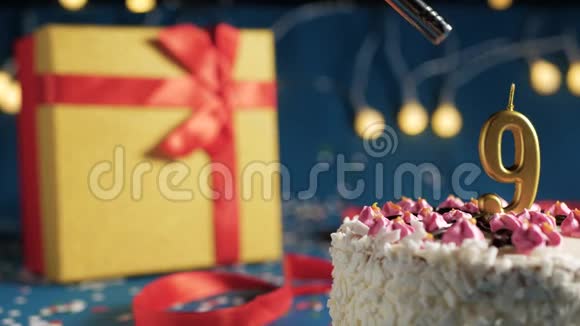 白色生日蛋糕9号金蜡烛由打火机点燃蓝色背景与灯和礼品黄盒子捆绑视频的预览图