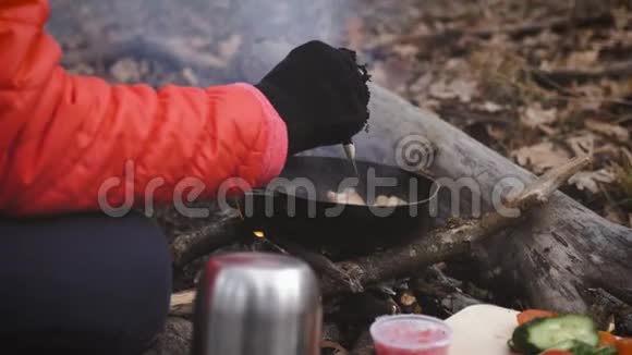 远足时在篝火上做饭一个女孩在篝火上用平底锅准备鸡蛋和西红柿和培根在露营视频的预览图