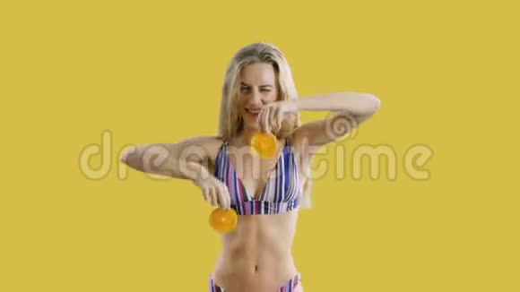 年轻漂亮的女孩正微笑着手里拿着黄色背景上的橘子快乐健康瘦女人期待视频的预览图