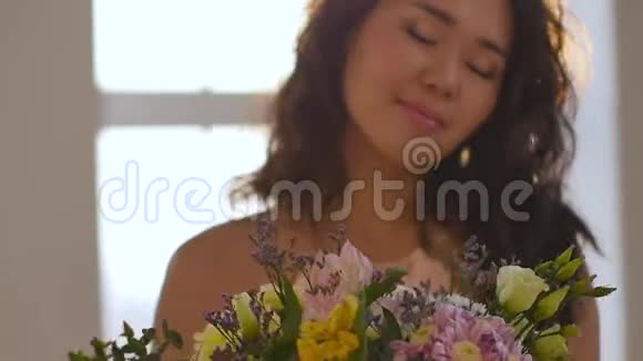 一位美丽的亚洲年轻女子的肖像她穿着一件精致的粉红色连衣裙手里拿着春天的花一个女人视频的预览图