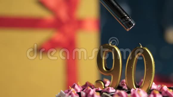 生日蛋糕数字90金色蜡烛用打火机点燃蓝色背景礼品黄色盒子用红丝带系好视频的预览图