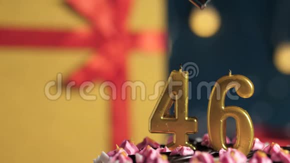 生日蛋糕46支金色蜡烛用打火机点燃蓝色背景礼品黄色盒子用红丝带绑好视频的预览图