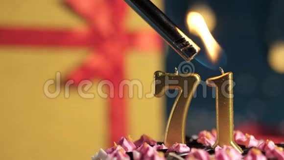 生日蛋糕71号金色蜡烛用打火机点燃蓝色背景礼品黄色盒子用红丝带系好视频的预览图