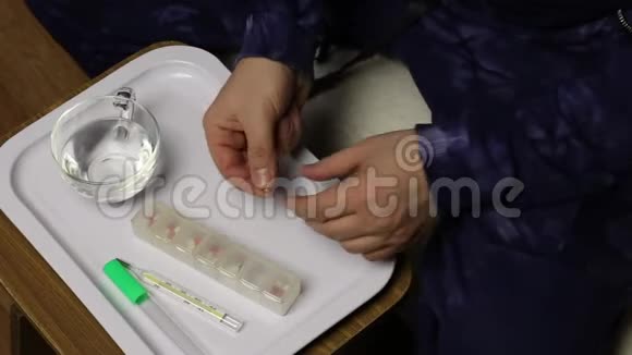 一个人手里拿着药丸和一杯水在他面前的托盘上放着一个平板盒里面装着几个细胞和一杯视频的预览图