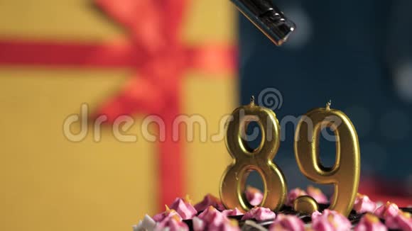 生日蛋糕89号金色蜡烛用打火机点燃蓝色背景礼品黄色盒子用红丝带绑好视频的预览图
