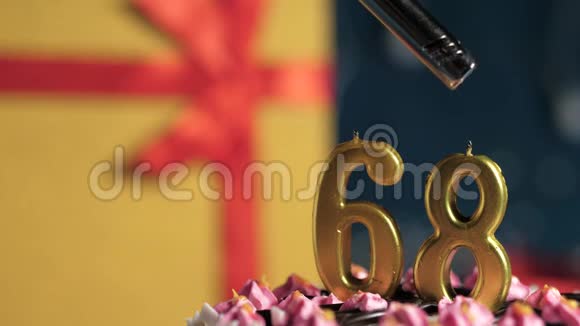 生日蛋糕数字68金蜡烛用打火机点燃蓝色背景礼品黄色盒子用红丝带绑好视频的预览图