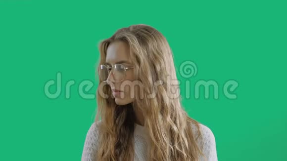 戴眼镜的严肃聪明的女孩在绿色屏幕背景下看相机的肖像一个聪明的少年微笑着视频的预览图