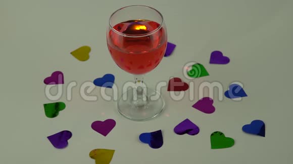 一杯白色背景的红酒心形纸屑的散射情人节庆祝活动概念视频的预览图