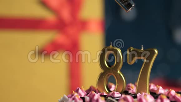 生日蛋糕87号金色蜡烛用打火机点燃蓝色背景礼品黄色盒子用红丝带系好视频的预览图
