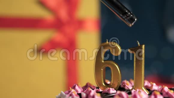 生日蛋糕数字61金蜡烛用打火机点燃蓝色背景礼品黄色盒子用红丝带系好视频的预览图