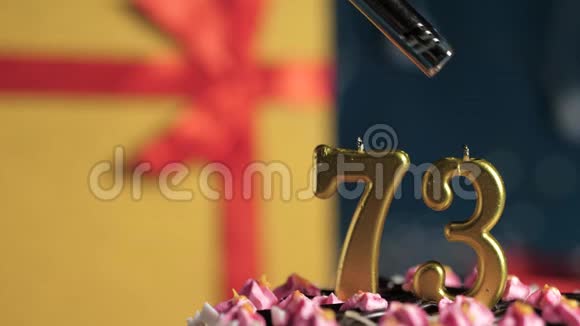 生日蛋糕编号73金色蜡烛用打火机点燃蓝色背景礼品黄色盒子用红丝带系好视频的预览图