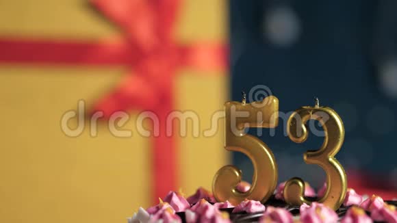 生日蛋糕编号53金色蜡烛用打火机点燃蓝色背景礼品黄色盒子用红丝带系好视频的预览图