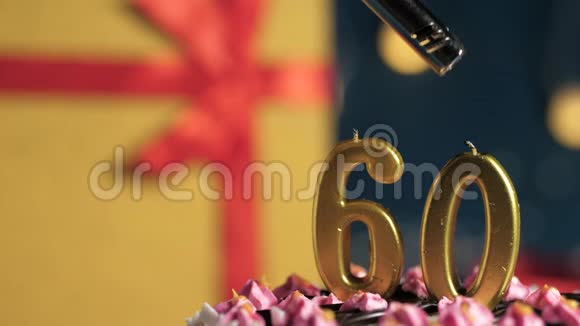 生日蛋糕数字60金蜡烛用打火机点燃蓝色背景礼品黄色盒子用红丝带系好视频的预览图