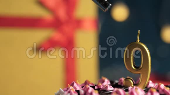 生日蛋糕9号金色蜡烛用打火机燃烧蓝色背景礼品黄色盒子用红色丝带绑起来关闭视频的预览图