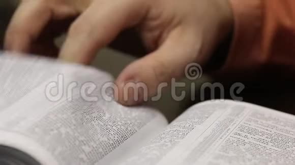 桌子上放着一本公开的圣经一个人慢慢地翻页寻找合适的地方特写镜头视频的预览图