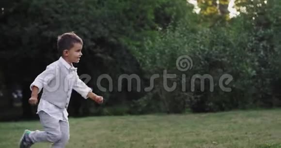 有魅力的5岁男孩跑得非常热情在一个大公园的中央看着摄像机视频的预览图