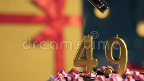 生日蛋糕49号金色蜡烛用打火机点燃蓝色背景礼品黄色盒子用红丝带系好视频的预览图