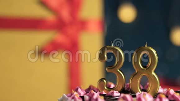 生日蛋糕38号金色蜡烛用打火机点燃蓝色背景礼品黄色盒子用红丝带系好视频的预览图