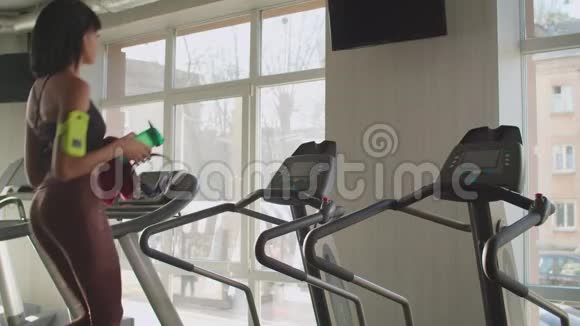 适合苗条的女人准备在跑步机上跑步视频的预览图