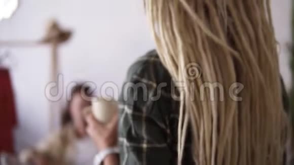 头发长长的金发女孩带着杯子来找她的男朋友从后面的录像一对年轻的情侣视频的预览图