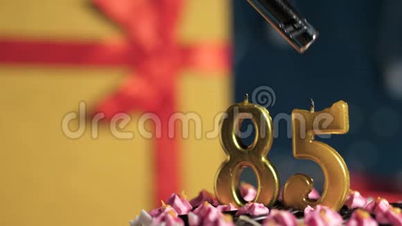 生日蛋糕85号金色蜡烛用打火机点燃蓝色背景礼品黄色盒子用红丝带绑好视频的预览图