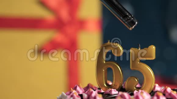 生日蛋糕65号金色蜡烛用打火机点燃蓝色背景礼品黄色盒子用红丝带系好视频的预览图
