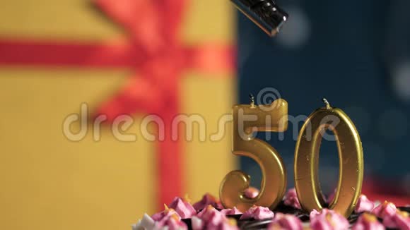 生日蛋糕50支金色蜡烛用打火机点燃蓝色背景礼品黄色盒子用红丝带绑好视频的预览图