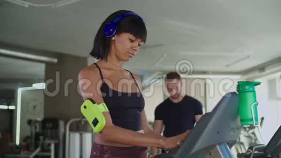 健身教练帮助妇女在健身房使用跑步机视频的预览图