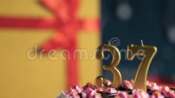 生日蛋糕37号金色蜡烛用打火机点燃蓝色背景礼品黄色盒子用红丝带系好视频的预览图