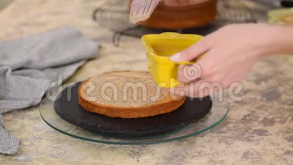 无法辨认的女性糖果手用硅制料刷将海绵蛋糕与甜焦糖糖浆浸泡在视频的预览图