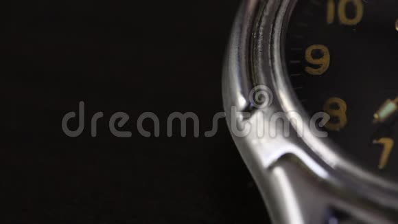 桌子上有一只手表部分表盘可见第二只手移动在黑色背景下拍摄特写镜头视频的预览图
