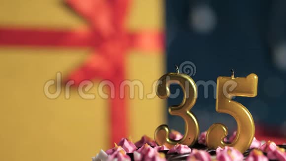 生日蛋糕数字35金色蜡烛用打火机燃烧蓝色背景礼品黄色盒子用红丝带系好视频的预览图