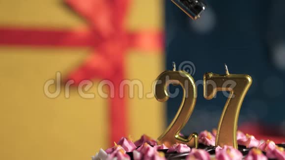 生日蛋糕27号金色蜡烛用打火机点燃蓝色背景礼品黄色盒子用红丝带系好视频的预览图