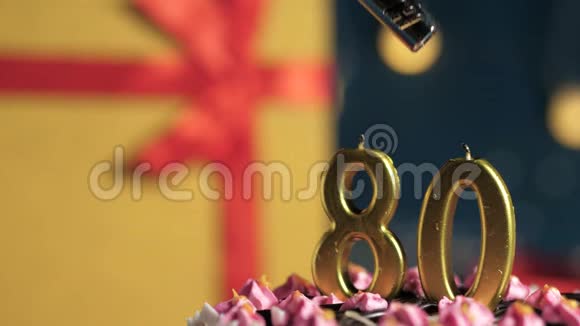 生日蛋糕数字80金蜡烛用打火机点燃蓝色背景礼品黄色盒子用红色丝带系好视频的预览图