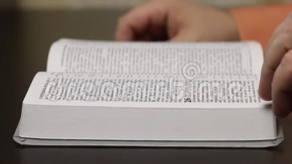 桌子上放着一本公开的圣经一个人慢慢地翻页寻找想要的章节特写镜头视频的预览图