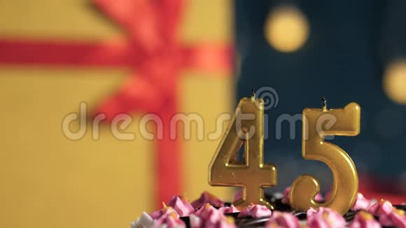 生日蛋糕45号金色蜡烛用打火机点燃蓝色背景礼品黄色盒子用红丝带系好视频的预览图