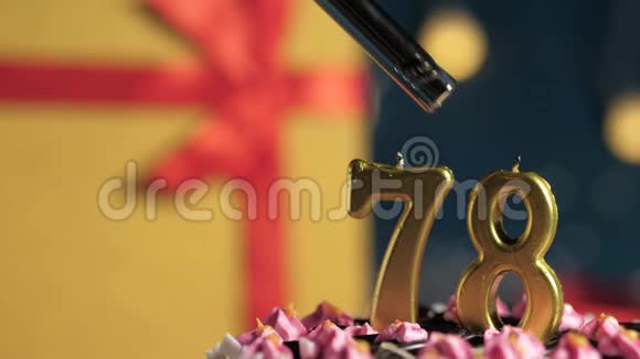 生日蛋糕78号金色蜡烛用打火机点燃蓝色背景礼品黄色盒子用红丝带好视频的预览图