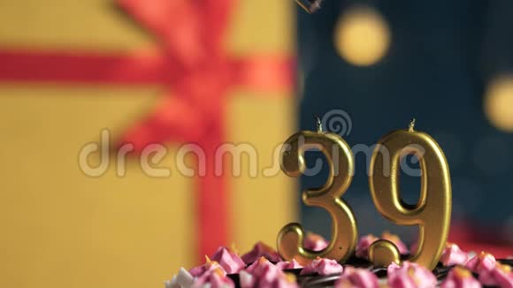 生日蛋糕39号金色蜡烛用打火机点燃蓝色背景礼品黄色盒子用红丝带系好视频的预览图