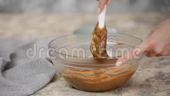 女人在碗里搅拌美味的巧克力奶油桌子上有搅拌器视频的预览图