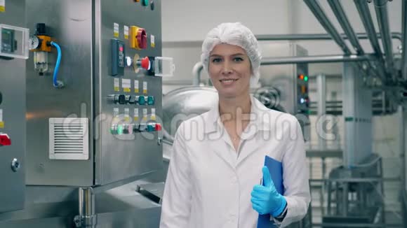 身着制服的女人微笑着站在乳品厂的房间里视频的预览图