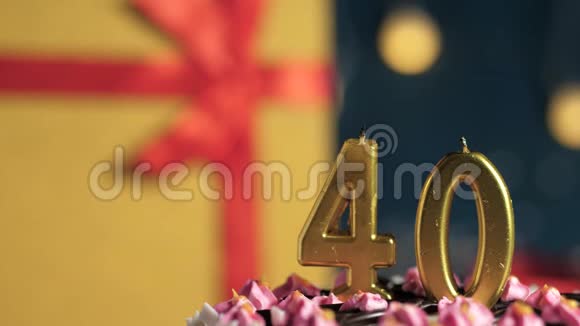 生日蛋糕40支金色蜡烛用打火机点燃蓝色背景礼品黄色盒子用红色丝带系好视频的预览图